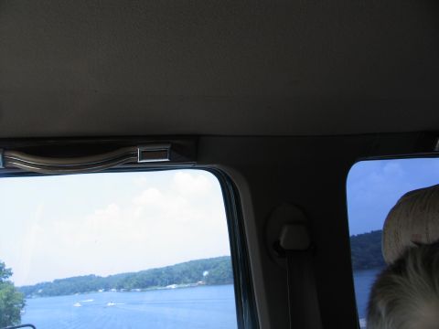 1995 Ford C-350 (Centurion Conversions) - Looking out from inside a vehicle at a lake scene with trees and boats.