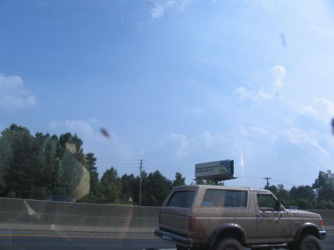 1995 Ford C-350 (Centurion Conversions) - A tan Ford Bronco is seen from the rear on a highway.