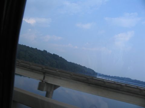 1995 Ford C-350 (Centurion Conversions) - Driving over a bridge with a scenic view of water and hills under a blue sky with clouds.