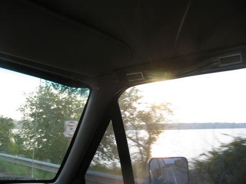 1995 Ford C-350 (Centurion Conversions) - View from the passenger side of a vehicle, looking out the window at trees and a body of water.