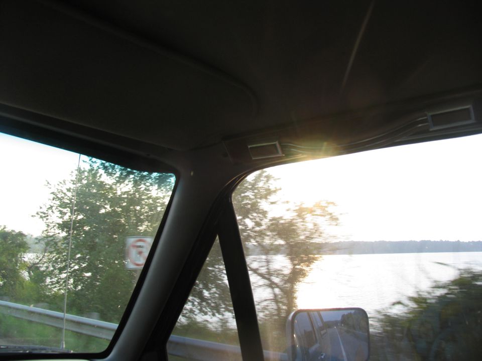 Interior view from passenger side showing dashboard and side window with trees and water outside