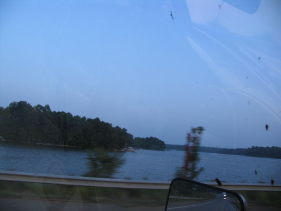 View of a lake with trees on the shore, seen through a car window