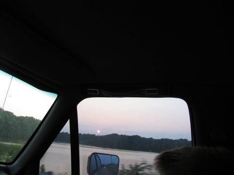 1995 Ford C-350 (Centurion Conversions) - Driving past a lake with the sun setting over the trees.