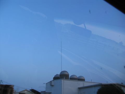 1995 Ford C-350 (Centurion Conversions) - View through a windshield shows reflections of buildings and sky, with a tall antenna visible.