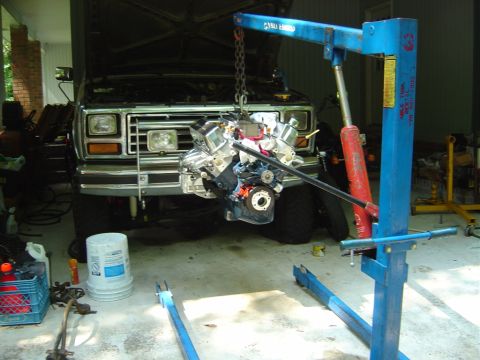 1986 Ford Bronco - Engine removal in progress for a 1986 Ford Bronco, with the engine suspended by a hoist.