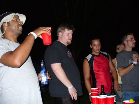 1991 Ford Probe - Several people are gathered outdoors at night, holding drinks and bottles.