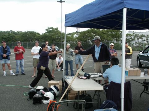 2001 Mercury Grand Marquis - An outdoor event with several people gathered around tables and a blue canopy, with helmets scattered on the ground.