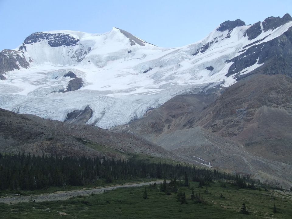 Mountains with a large glacier flowing down them, trees in the foreground