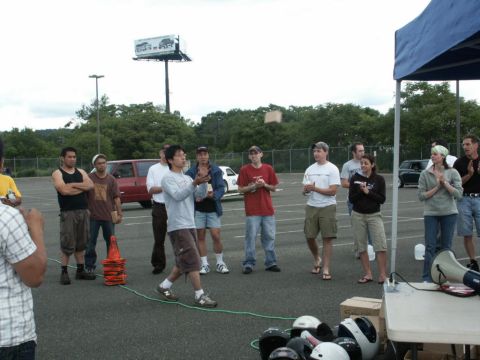 2001 Mercury Grand Marquis - People are gathered in a parking lot, watching a man throw a box while others clap.