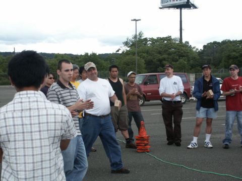 2001 Mercury Grand Marquis - Men gathered in a parking lot with a red van and a billboard in the background.