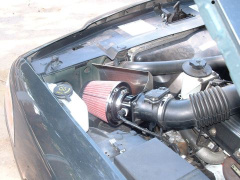 1998 Ford Crown Victoria - Under-hood view of a vehicle engine bay fitted with a red cone-style aftermarket air intake filter and metal heat shield.