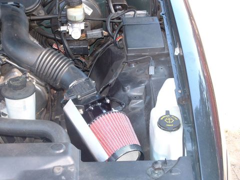 1998 Ford Crown Victoria - Engine bay showing a red cone air filter on a polished intake tube beside a white coolant overflow reservoir.