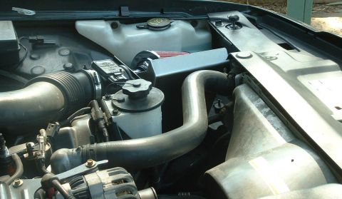 1998 Ford Crown Victoria - Top-down view of an engine bay showing the coolant reservoir, large rubber radiator hoses and air intake plumbing.