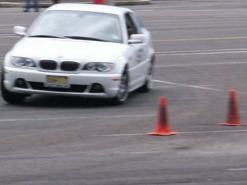 2001 Mercury Grand Marquis - A white BMW sedan is shown on a track, maneuvering around orange cones during what appears to be a driving event.