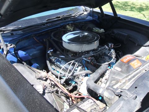 1974 Ford Ranchero - Engine bay view of a classic Ford with a V8 engine topped by a chrome round chromed air cleaner, black spark plug wires, and a visible Edel…