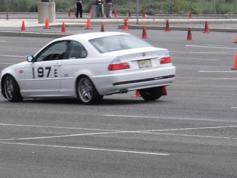 2001 Mercury Grand Marquis - White BMW E46 coupe navigates an autocross course marked by orange cones.