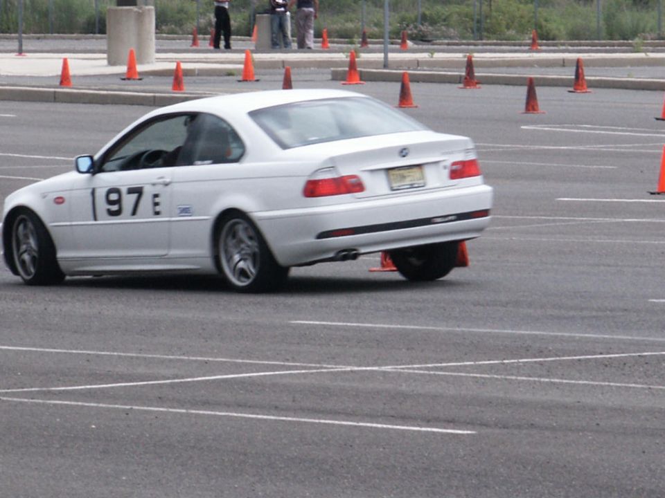 White BMW E46 coupe with '97 E' on the door, participating in an autocross event