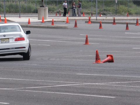 2001 Mercury Grand Marquis - A white BMW sedan navigates a course marked by orange traffic cones in an empty parking lot.