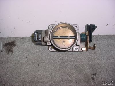 1998 Ford Crown Victoria - used aluminum throttle body assembly with attached position sensor and linkage, photographed on light carpet.