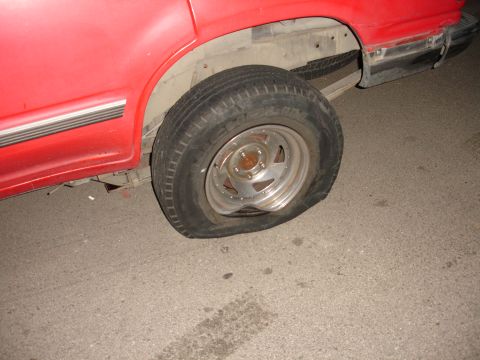 1992 Ford Explorer - The rear passenger side tire on this red vehicle is completely flat.