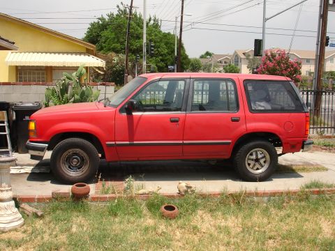 1992 Ford Explorer - A red SUV is parked on a driveway in front of a yellow house.