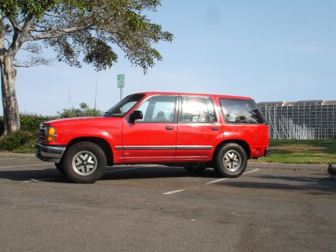 1992 Ford Explorer - Side view of a red 1992 Ford Explorer parked in a lot under a tree.