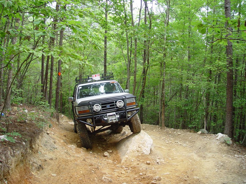 White Ford Bronco with roof rack and winch on a rocky trail