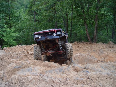 1996 Ford Bronco - Modified 1996 Ford Bronco tackling a challenging off-road course with large tires and lifted suspension.