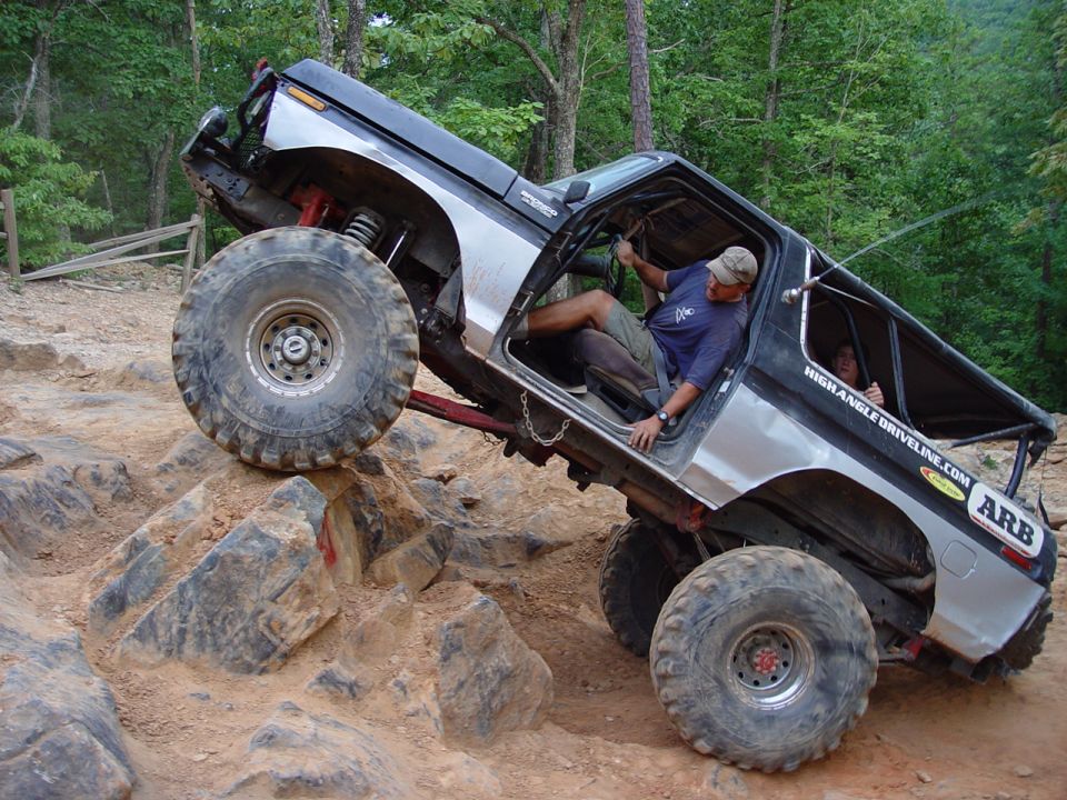 Modified Ford Bronco climbing steep rocky terrain with driver inside