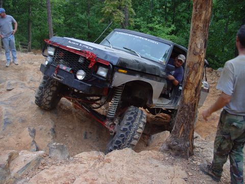 1996 Ford Bronco - This heavily modified off-road vehicle is attempting to climb a steep, rocky terrain, with "ALASKAN EXTREME" visible on its hood.