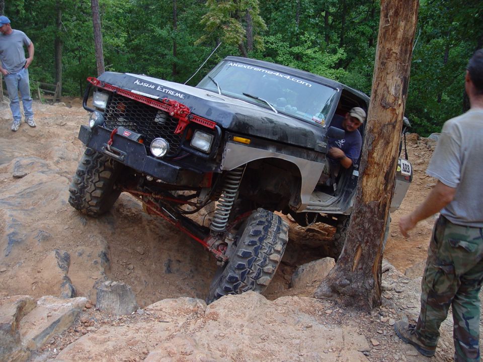 Modified off-road vehicle with "ALASKAN EXTREME" on hood, navigating rocks