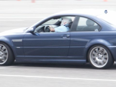 2001 Mercury Grand Marquis - Driver in helmet steers a blue coupe on a track.