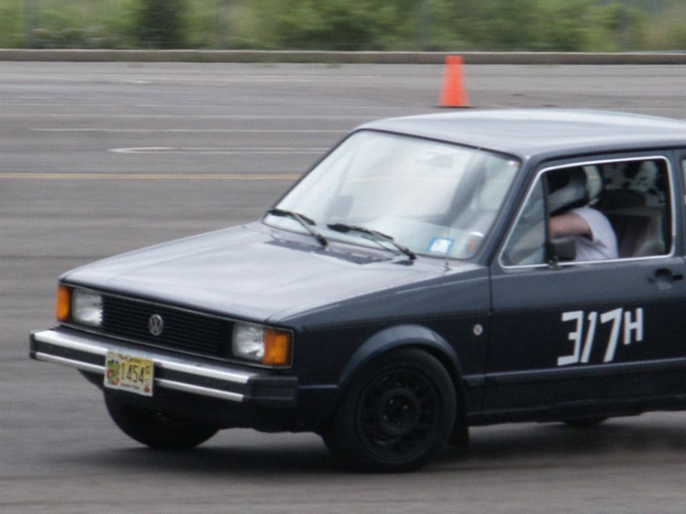 Dark gray Volkswagen Rabbit GTI with racing numbers '3/7H' on the door, on a track