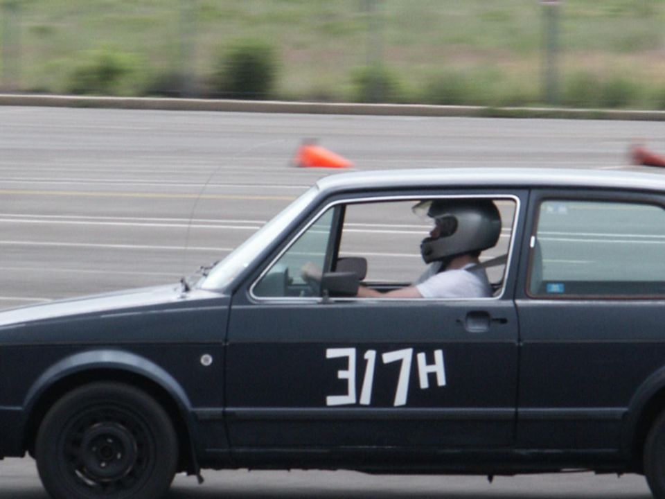 Dark hatchback with white racing numbers '317H' on the side, driver wears a helmet