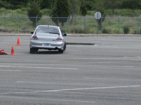 2001 Mercury Grand Marquis - A silver sedan navigates a course marked by orange traffic cones on an asphalt lot.