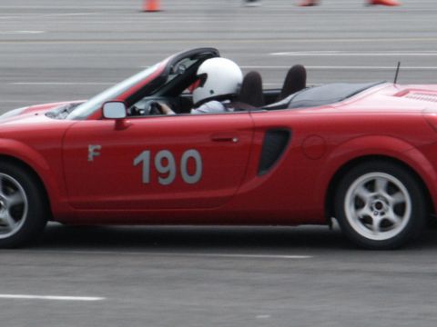 2001 Mercury Grand Marquis - A red convertible sports car with racing number 190 drives on a track with a driver wearing a white helmet.