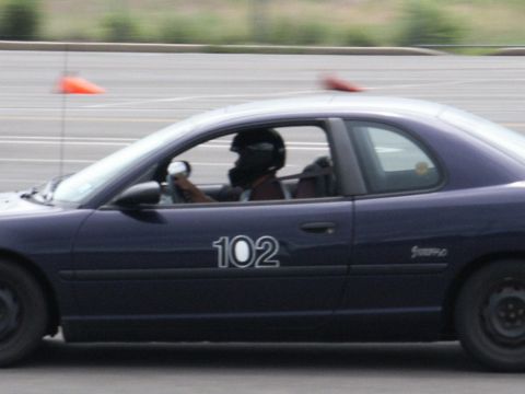 2001 Mercury Grand Marquis - A driver in a helmet races a dark blue coupe with the number 102 visible on its side.