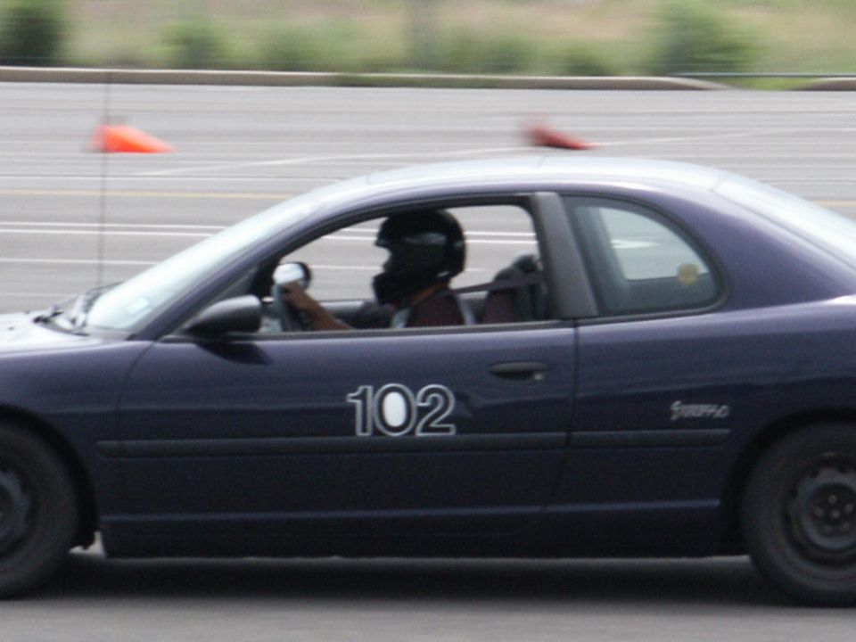 Dark blue coupe with number 102 on the side, driver wearing helmet
