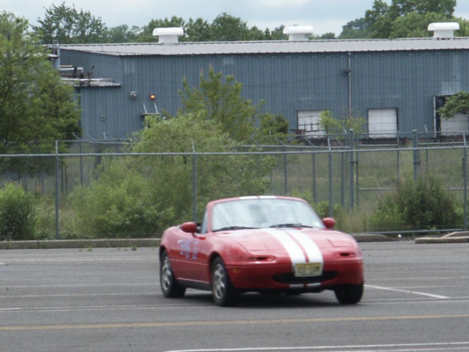 Red convertible sports car with white racing stripes on the hood, parked in a lot