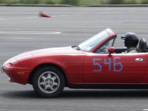 2001 Mercury Grand Marquis - A red convertible with the number 546 on its side is seen on a track with a driver wearing a helmet.