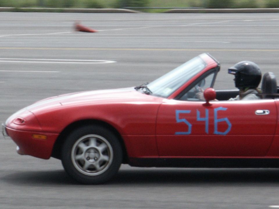 Red convertible with blue number 546 on door, driver in helmet, side view
