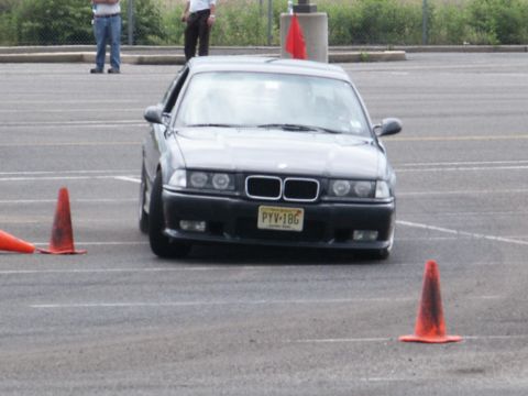 2001 Mercury Grand Marquis - A BMW E36 navigates a course marked by orange traffic cones on a paved lot.