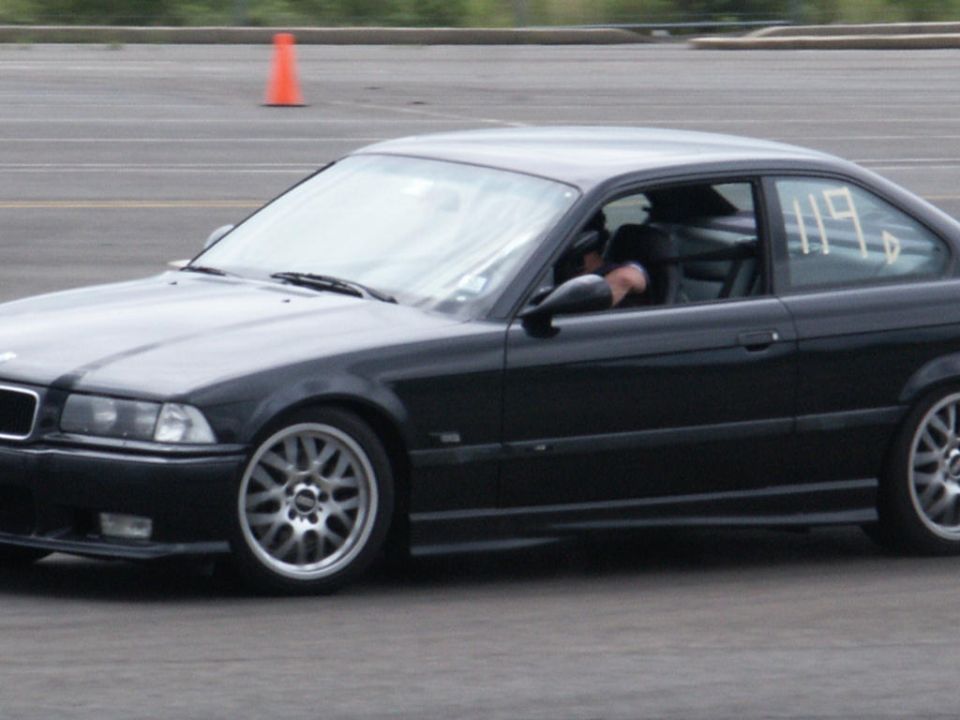 Black coupe with racing number 119 on the driver's side window, seen from the front-right