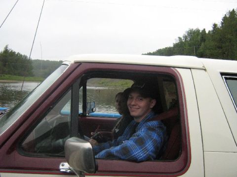 1995 Ford Bronco - Two people are inside a truck, with a body of water and trees visible through the windows.