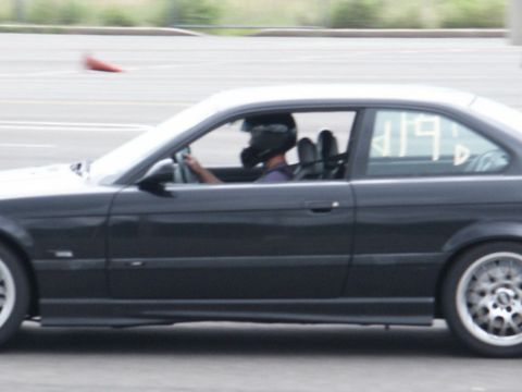 2001 Mercury Grand Marquis - Driver in racing helmet steers a dark coupe on a track, with number 419 visible on the window.