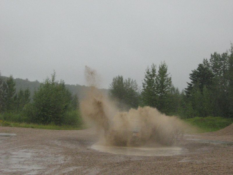 1995 Ford Bronco driving through a muddy puddle, kicking up a large splash