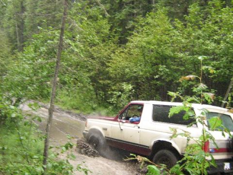 1995 Ford Bronco - This 1995 Ford Bronco navigates a challenging muddy trail in a wooded area.