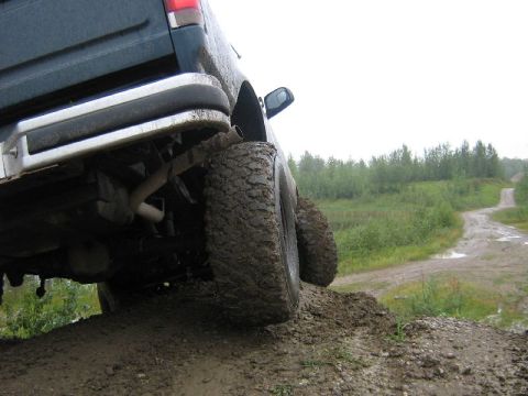 1995 Ford Bronco - SUV with aggressive tires navigates a muddy, off-road path.