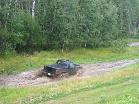 1995 Ford Bronco - Black 1995 Ford Bronco navigates a challenging muddy off-road path.