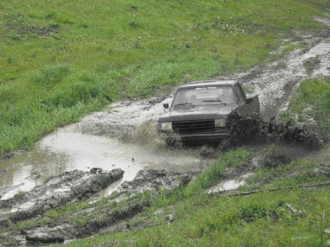 1995 Ford Bronco - Pickup truck navigating a challenging muddy off-road course.